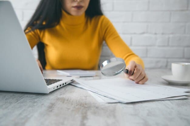 A person reviewing a credit report on a laptop, with a magnifying glass hovering over the report, highlighting the importance of detailed examination.