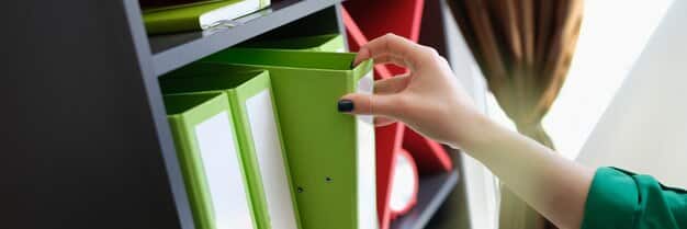 A hand organizing papers and files in a folder, symbolizing the importance of keeping accurate records of student loan communication.