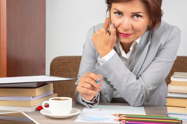 A teacher is sitting at a desk, reviewing loan documents with a focused expression. A calculator and a cup of coffee are also on the desk.