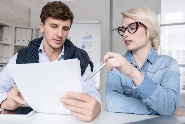 A student talking to a financial aid advisor in an office setting. Both are looking at a document on the desk.