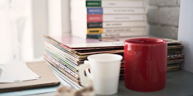 A close-up shot of a freelancer's workspace with neat stacks of receipts, an open spreadsheet on a laptop, and a pen and notebook. The image conveys a sense of organization and attention to detail in tracking finances.