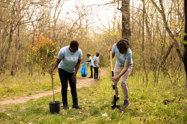 A diverse group of people participating in a community service event, possibly cleaning up a park or planting trees. The scene conveys a sense of purpose, unity, and dedication to public service.